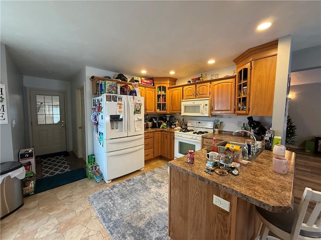 kitchen with sink, white appliances, a kitchen breakfast bar, and kitchen peninsula