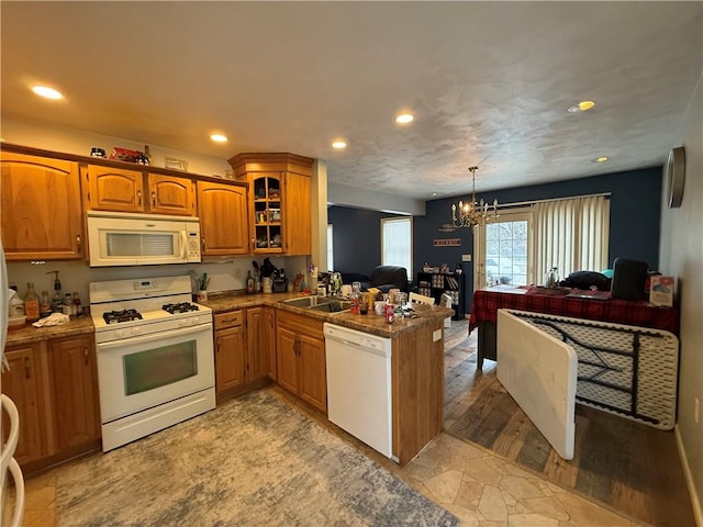 kitchen featuring white appliances, kitchen peninsula, pendant lighting, a notable chandelier, and sink