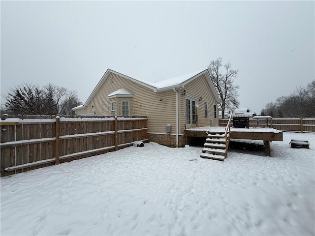 snow covered rear of property with a deck