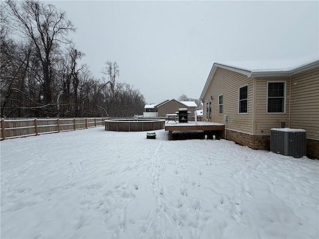 snowy yard featuring a pool side deck and central AC unit