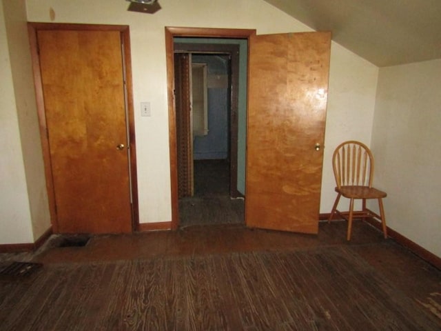 empty room featuring dark wood-type flooring and vaulted ceiling