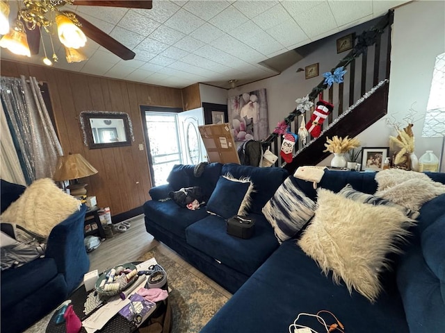 living room with ceiling fan, hardwood / wood-style floors, and wooden walls