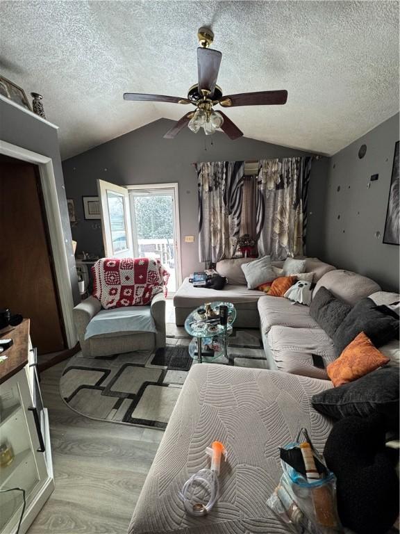 living room featuring a textured ceiling, ceiling fan, and vaulted ceiling