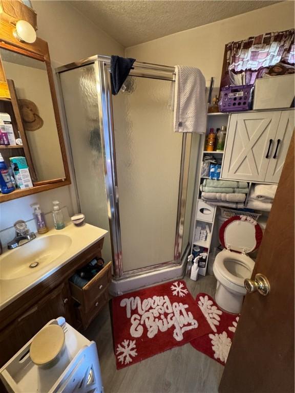 bathroom featuring hardwood / wood-style flooring, a textured ceiling, walk in shower, and vanity