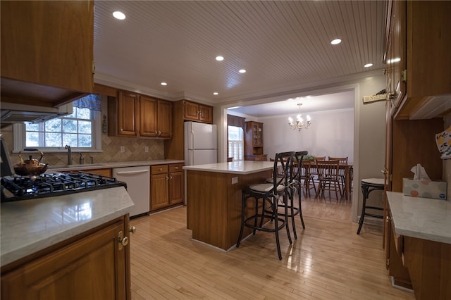 kitchen featuring hanging light fixtures, a center island, dishwashing machine, white refrigerator, and a kitchen bar