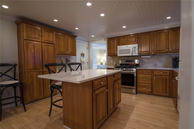 kitchen with a kitchen island, backsplash, gas stove, and a breakfast bar area