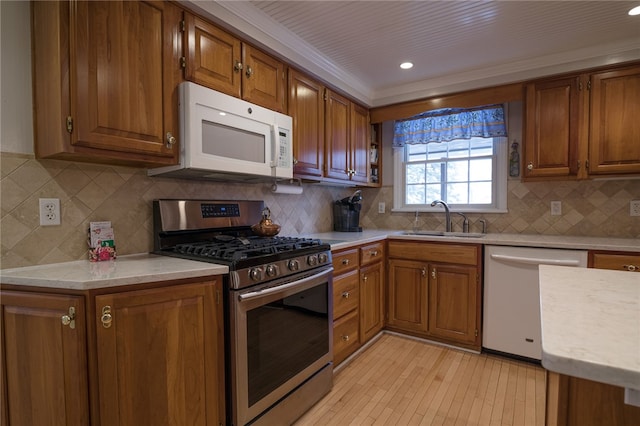 kitchen with dishwashing machine, backsplash, stainless steel range with gas cooktop, and sink