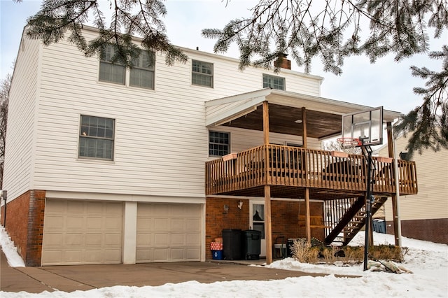 snow covered rear of property with a garage and a wooden deck