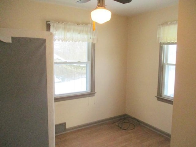 empty room with ceiling fan, hardwood / wood-style floors, and a wealth of natural light