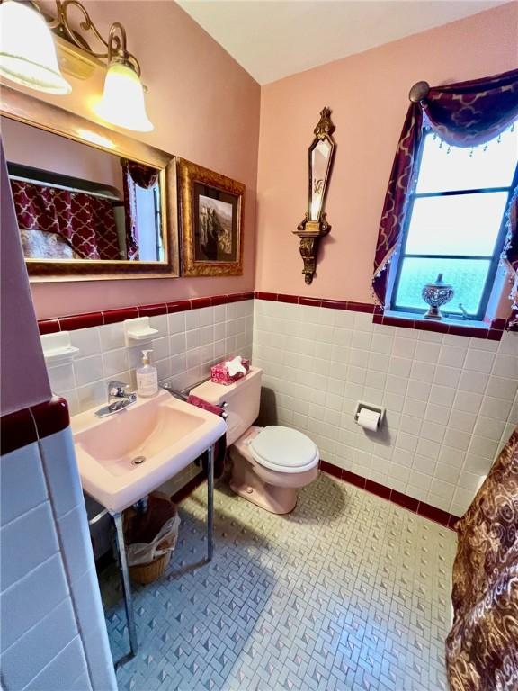 bathroom featuring tile walls, tile patterned flooring, sink, and toilet