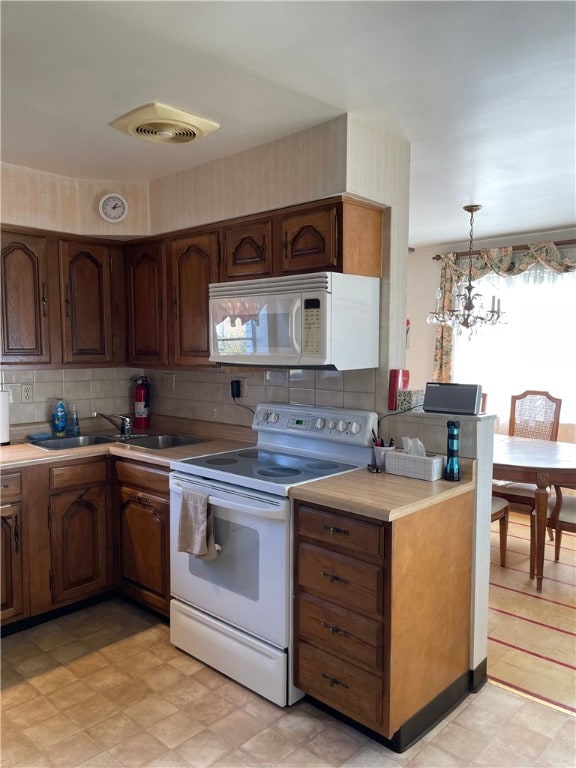 kitchen with white appliances, a notable chandelier, sink, decorative light fixtures, and tasteful backsplash