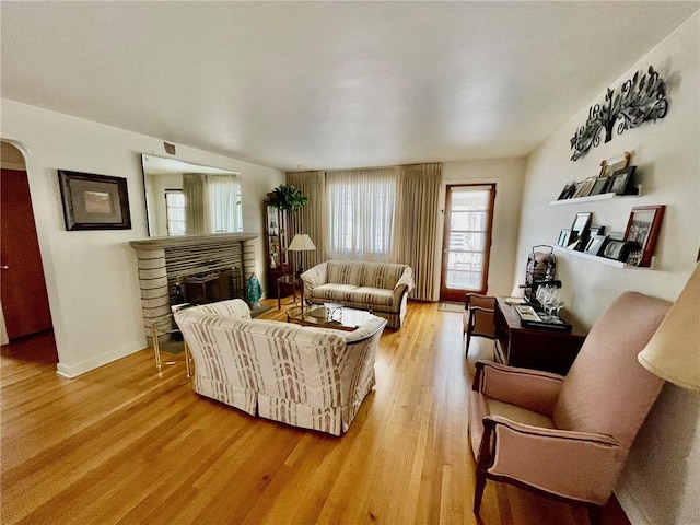 living room featuring a brick fireplace and light hardwood / wood-style floors