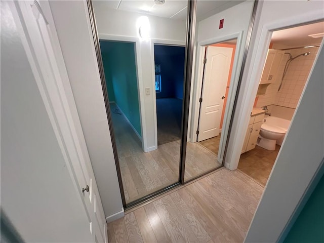 interior space with toilet, tiled shower / bath combo, and hardwood / wood-style floors