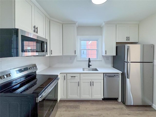 kitchen featuring appliances with stainless steel finishes, light hardwood / wood-style flooring, white cabinetry, and sink