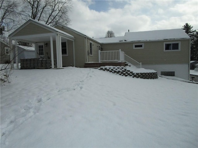 snow covered rear of property featuring covered porch