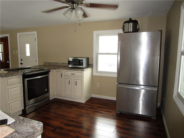 kitchen with kitchen peninsula, appliances with stainless steel finishes, light stone countertops, and dark hardwood / wood-style flooring