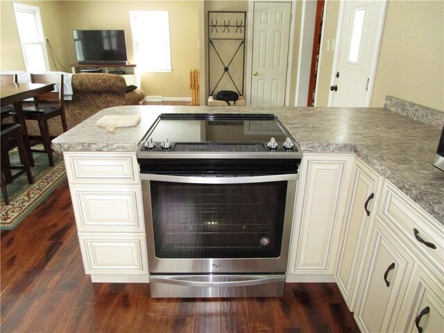 kitchen featuring kitchen peninsula, stainless steel electric range oven, and dark wood-type flooring