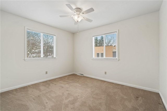 carpeted spare room with ceiling fan and a wealth of natural light