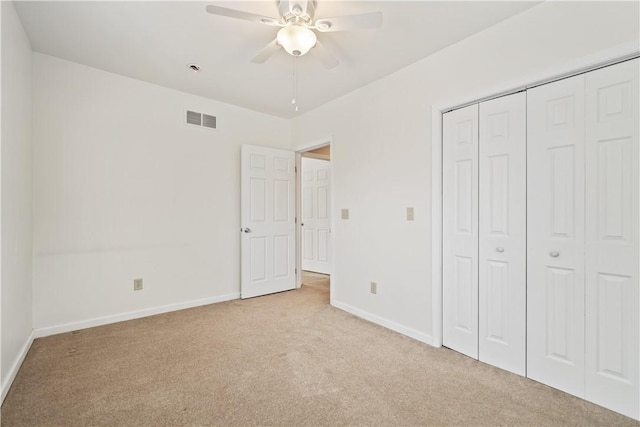 unfurnished bedroom featuring a closet, ceiling fan, and light colored carpet