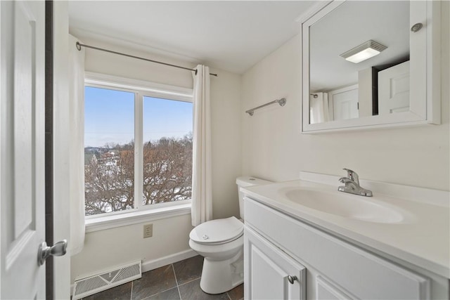 bathroom featuring toilet, vanity, and plenty of natural light