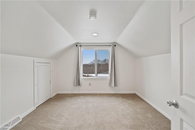 bonus room with lofted ceiling and light colored carpet