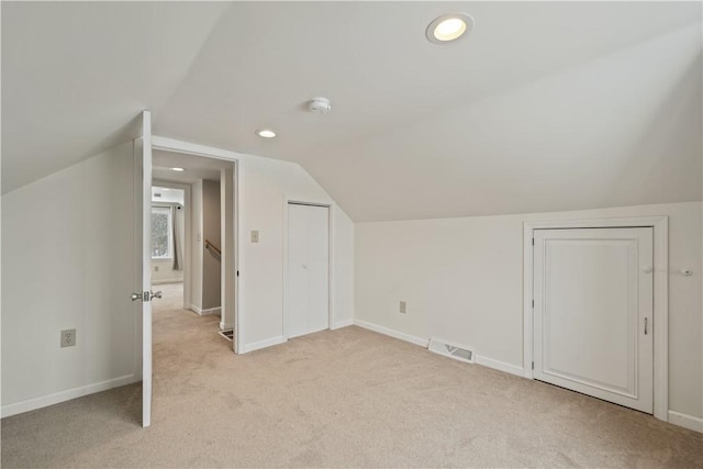 bonus room with vaulted ceiling and light colored carpet