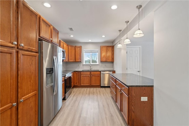 kitchen featuring light hardwood / wood-style flooring, decorative light fixtures, appliances with stainless steel finishes, dark stone countertops, and sink