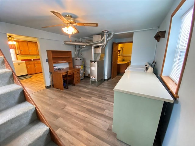 interior space featuring water heater, ceiling fan, washer and clothes dryer, and hardwood / wood-style floors