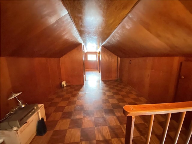 additional living space featuring vaulted ceiling and wooden walls