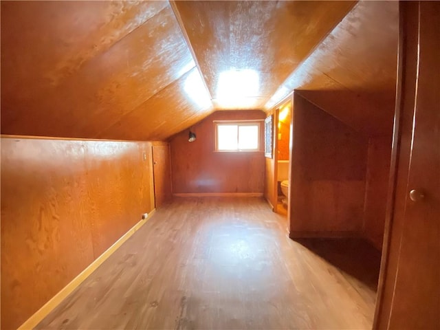 bonus room with hardwood / wood-style floors and vaulted ceiling