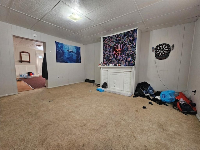 interior space with wood walls, carpet floors, and a paneled ceiling