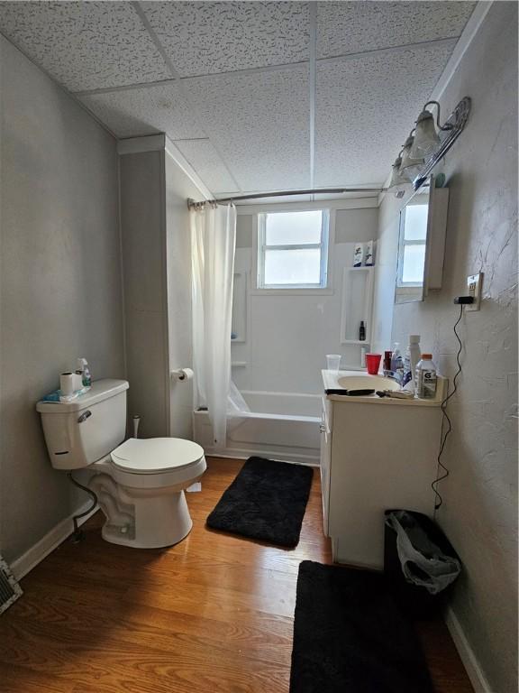 full bathroom featuring toilet, a paneled ceiling, shower / tub combo with curtain, wood-type flooring, and vanity