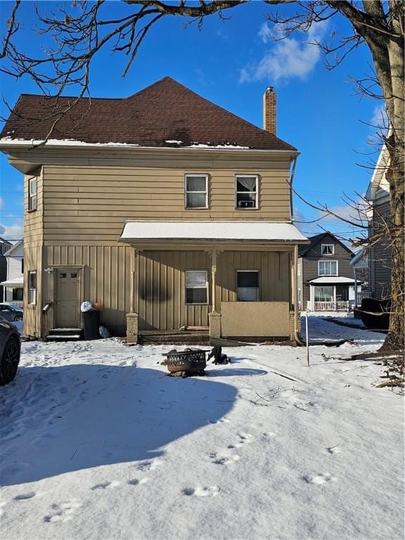 snow covered back of property with covered porch