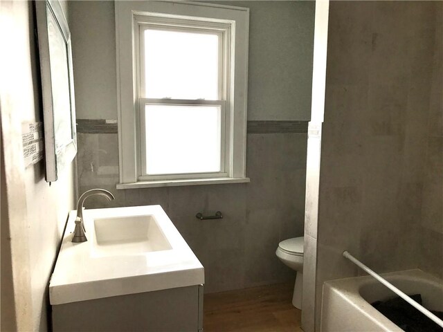 bathroom featuring a bathtub, hardwood / wood-style floors, vanity, and toilet