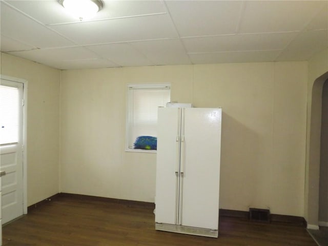 spare room with dark wood-type flooring and a paneled ceiling