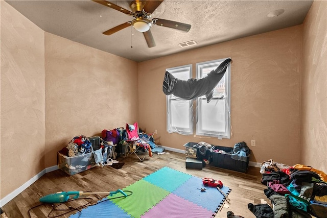 game room with a textured ceiling, ceiling fan, and light hardwood / wood-style floors