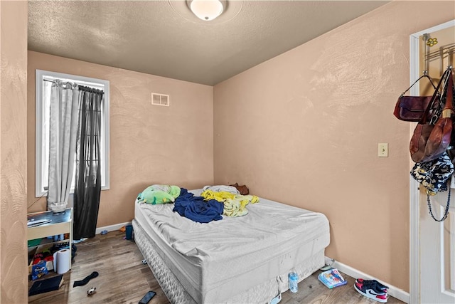 bedroom with light wood-type flooring and a textured ceiling