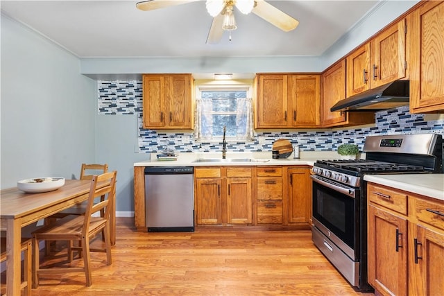 kitchen with stainless steel appliances, light wood-type flooring, ceiling fan, decorative backsplash, and sink