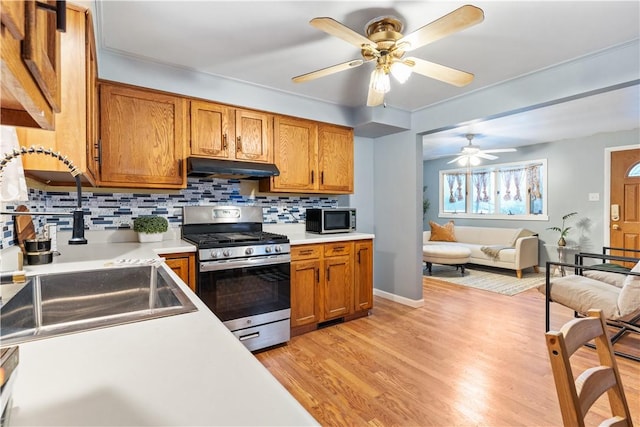 kitchen featuring light hardwood / wood-style floors, stainless steel appliances, ceiling fan, sink, and tasteful backsplash