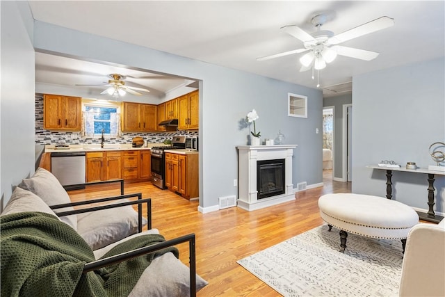 living room featuring light hardwood / wood-style floors, ceiling fan, and sink