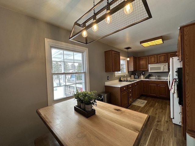 kitchen featuring decorative light fixtures, white appliances, sink, and dark wood-type flooring