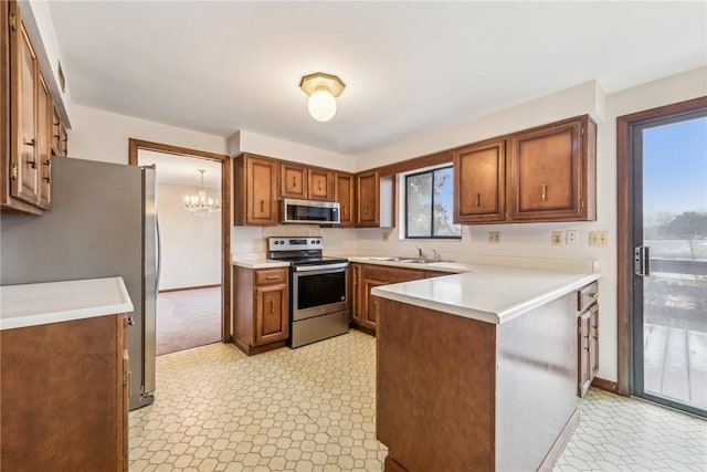 kitchen featuring sink, a chandelier, kitchen peninsula, and appliances with stainless steel finishes