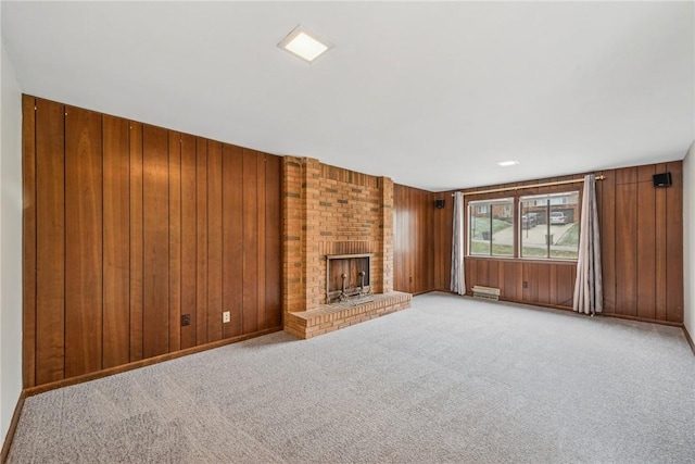 unfurnished living room featuring wooden walls, a brick fireplace, and light carpet