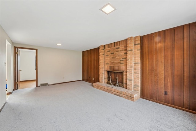 unfurnished living room featuring wooden walls, a fireplace, and light carpet