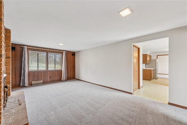 unfurnished living room featuring light colored carpet and wooden walls