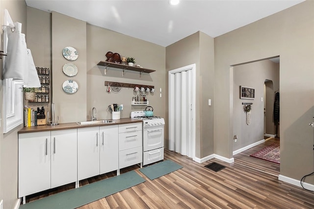 kitchen with white cabinets, wood counters, hardwood / wood-style flooring, sink, and white gas range