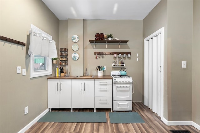 kitchen with white cabinets, hardwood / wood-style floors, gas range gas stove, and sink