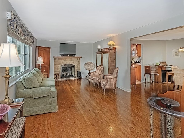 living room featuring hardwood / wood-style flooring and a stone fireplace