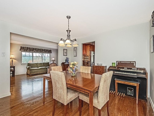 dining area with a notable chandelier and dark hardwood / wood-style flooring