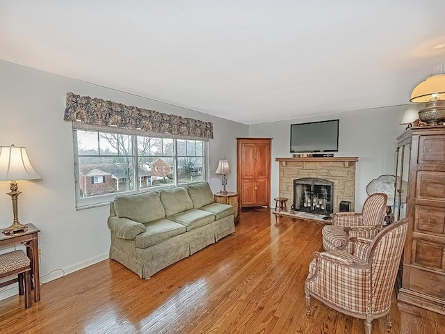 living room featuring a stone fireplace and hardwood / wood-style flooring